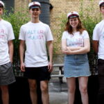 Fire nybagte studenter med studenterhuer på og en t-shirt med teksten: Alt er muligt