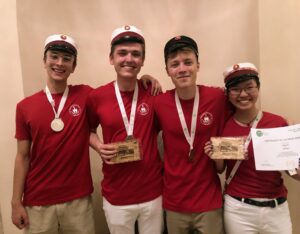 Tre drenge og en pige i røde t-shirts. Finalister ved biologiolympiaden 2022. Alle fire med medaljer.