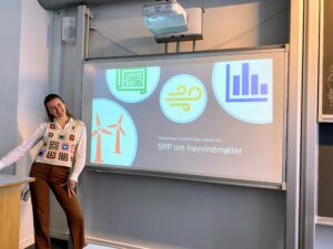 Gefion Science Fair 2023. En pige foran tavle med forsiden af sit SRP-projekt om havvindmøller.