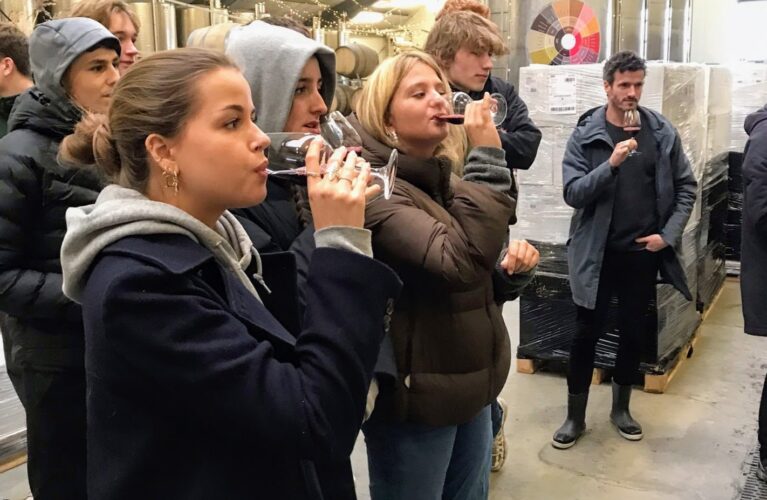 En gruppe elever smager på kirsebærvin i en stor hal til vinproduktion
