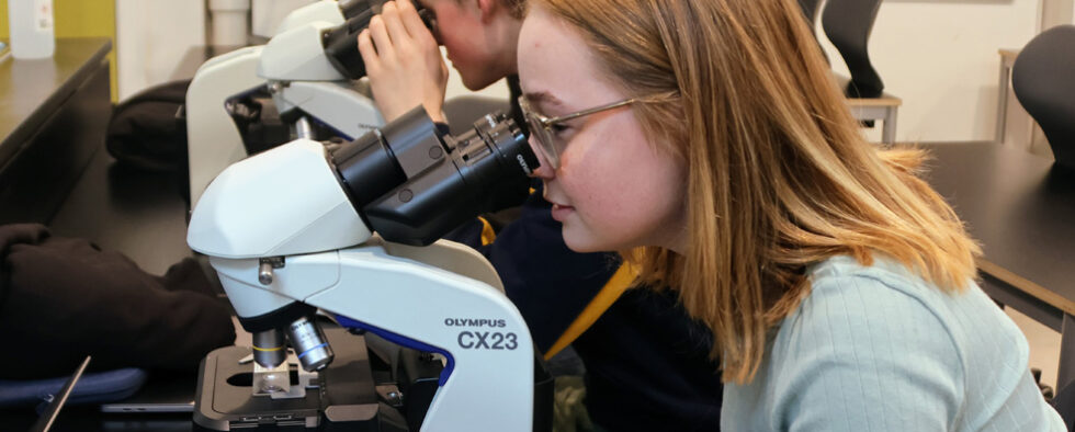 En pige ser i et mikroskop