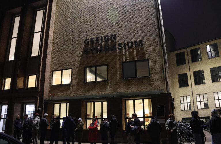 Bygningen med Gefion Gymnasium set udefra om aftenen, med en lang kø ind til Orienteringsaften 2025