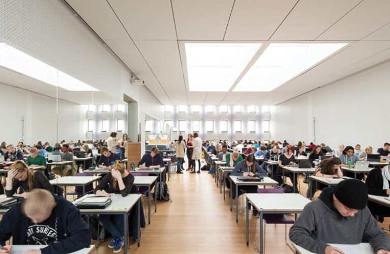 Elever sidder i rækker til eksamen i en stor sal