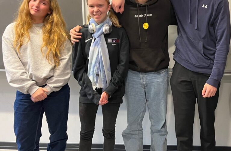 To piger og to drenge står ved siden af hinanden og smiler til kameraet