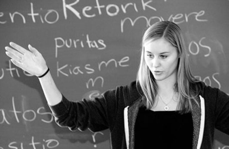 Elev der taler og gestikulerer foran tavle i klasseværelset