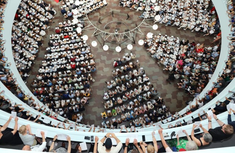 Dimission 2022. Rotunden set oppe fra med stundeter siddende på stole i stueetagen og etagerne fyldt op af mennesker.. Foto Dansk Skolefoto