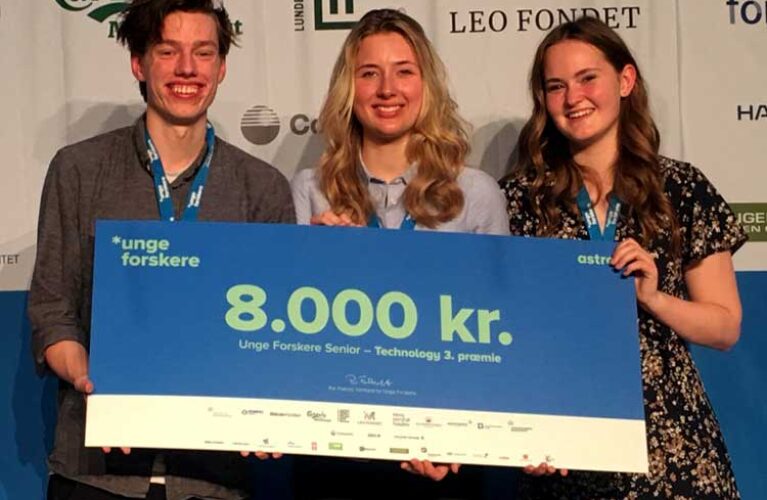 Tre glade elever der står med en stor check på 8.000 kr.