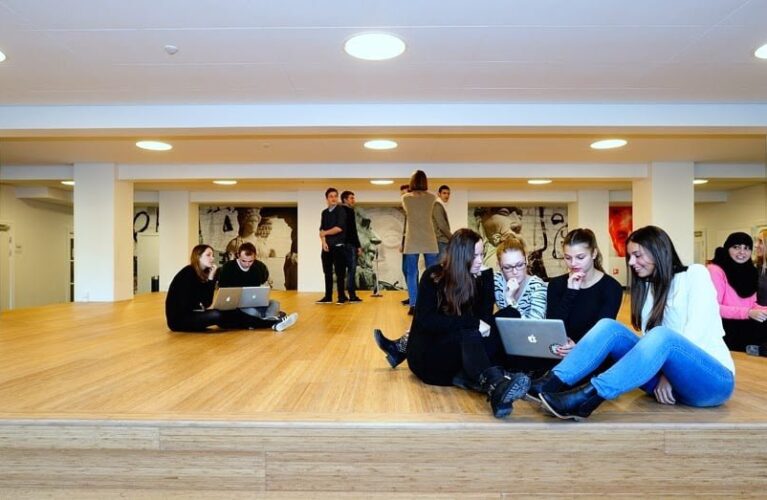 Grupper af elever der sidder på gulvet omkring en bærbar computer